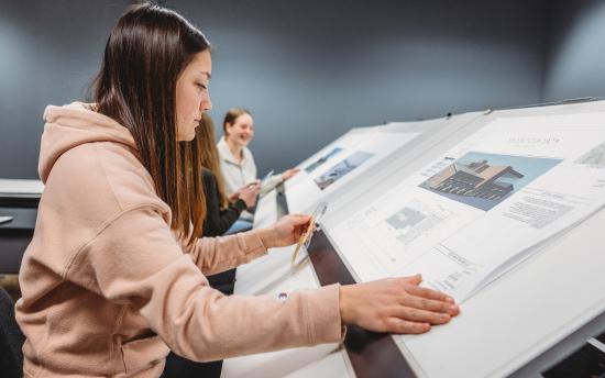 Three students reviewing blueprints for the architectural drafting and design program